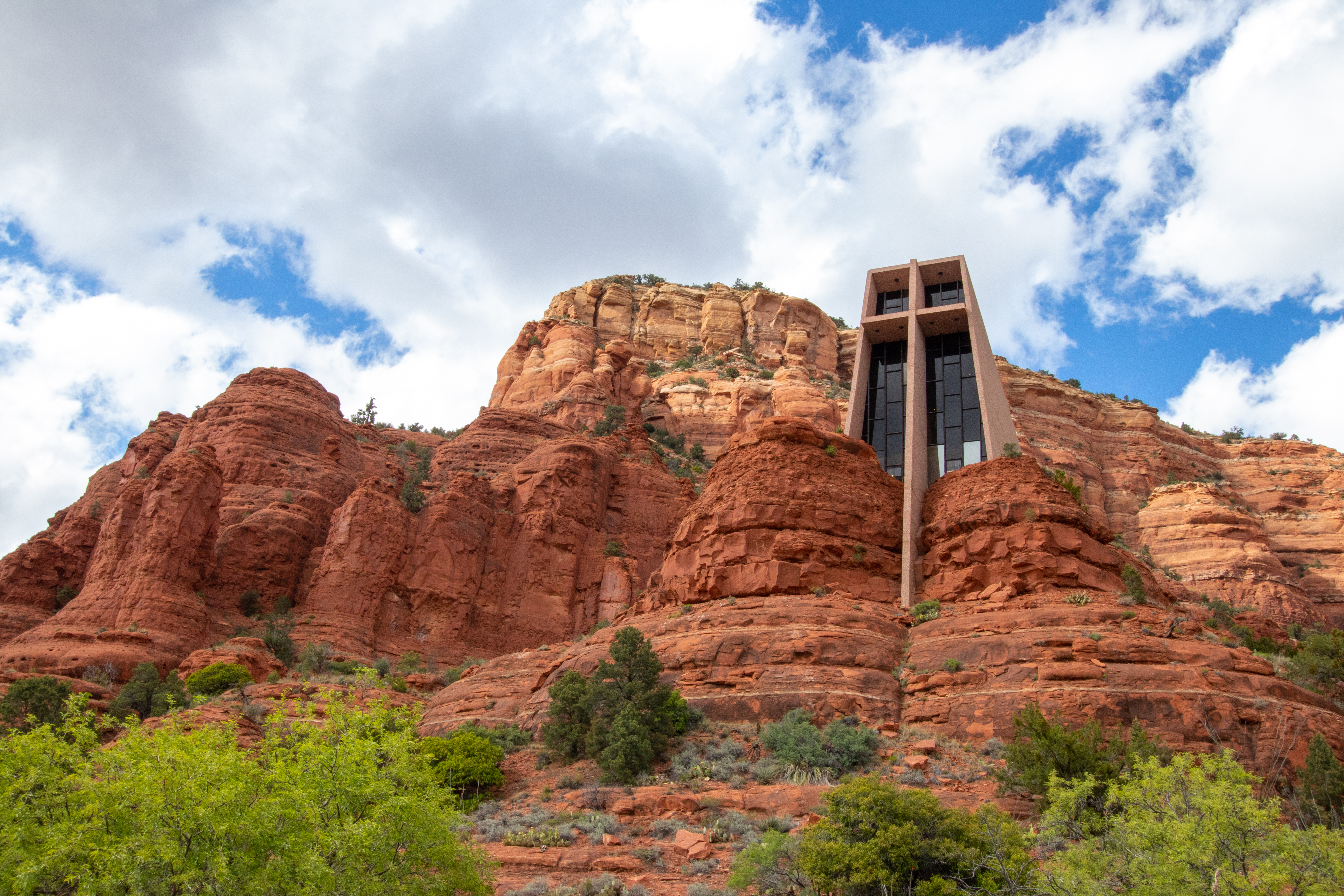 Chapel of the Holy Cross in the red rocks of Sedona, Arizona with blue sky and white clouds.